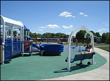 A playground with a unitary tile surface is accessible from all directions.